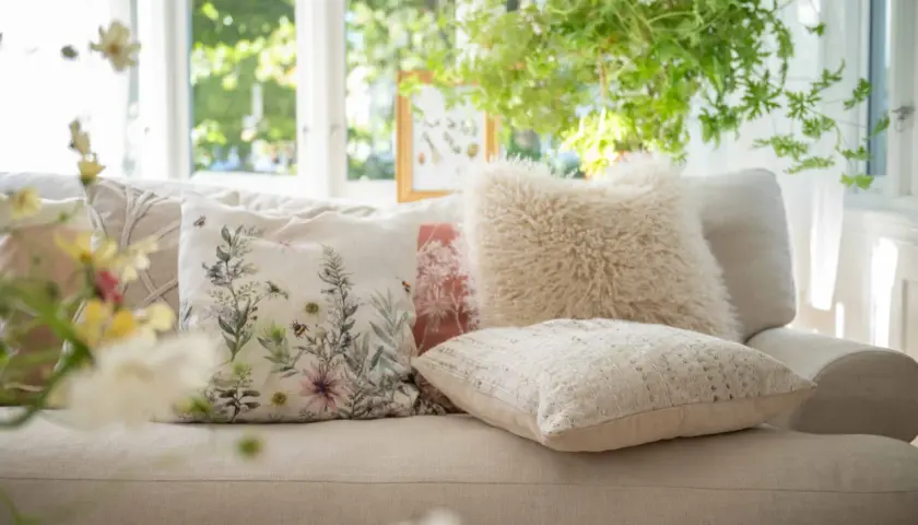 Mysiga kuddar i soffan inspiration: en blommig kudde med bin, en fluffig beige kudde och en texturerad ljus kudde skapar en ombonad känsla.