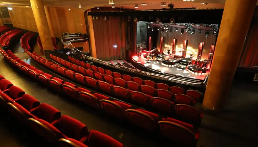 Tomma röda sammetsstolar i en teater, redo för publiken. Scenen är upplyst med instrument och redo för en konsert. En av många fina konsertlokaler i Stockholm.