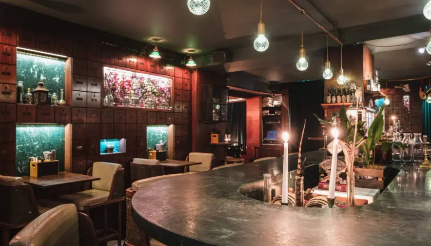 Mysig bar i Stockholm med mörka trädetaljer, gröna marmorbänkar och levande ljus. Perfekt för en romantisk date night.
