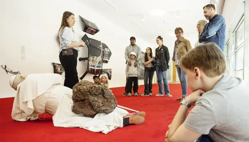 En grupp besökare, inklusive barn, lyssnar på en guide vid en konstinstallation på Moderna Museet Stockholm.