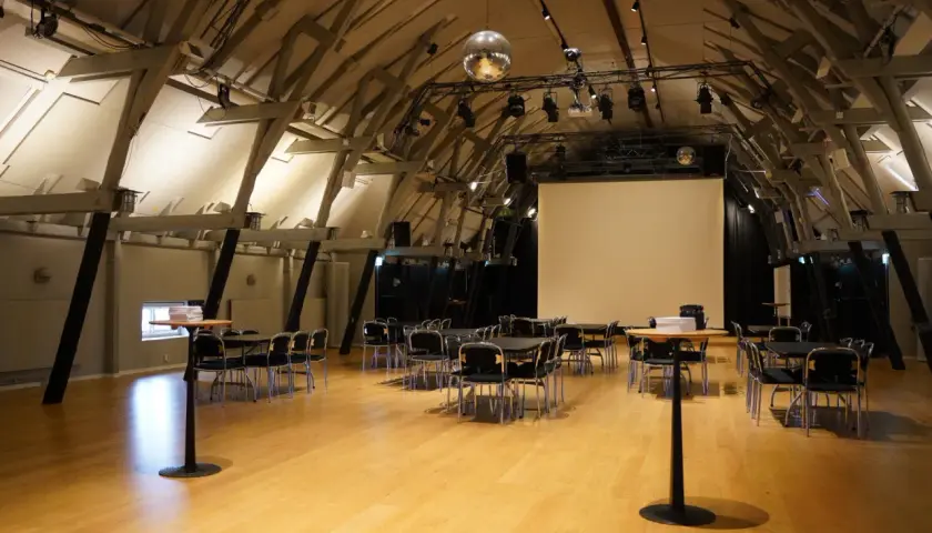 Stora, ljusa lokaler med trägolv och synliga takbjälkar, redo för ett event i workshop Stockholm.