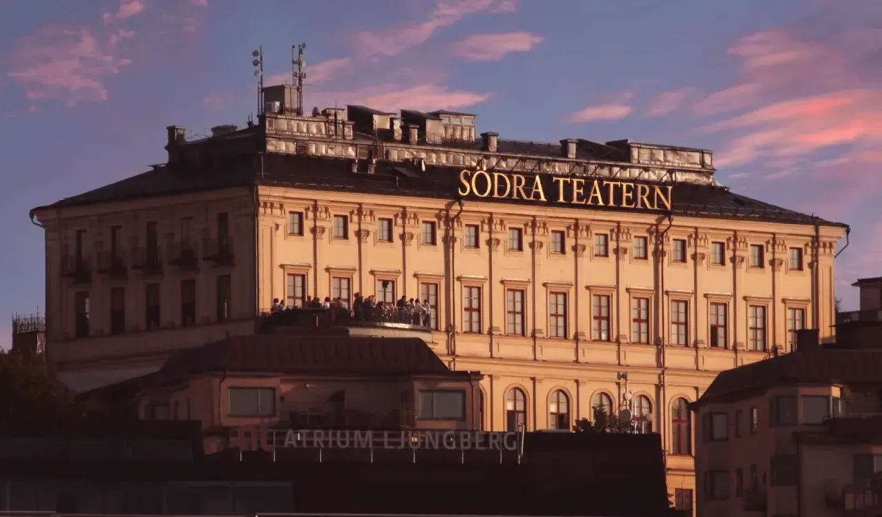 Södra Teatern, en ikonisk byggnad vid Mosebacke, badar i kvällssolens rosa sken.