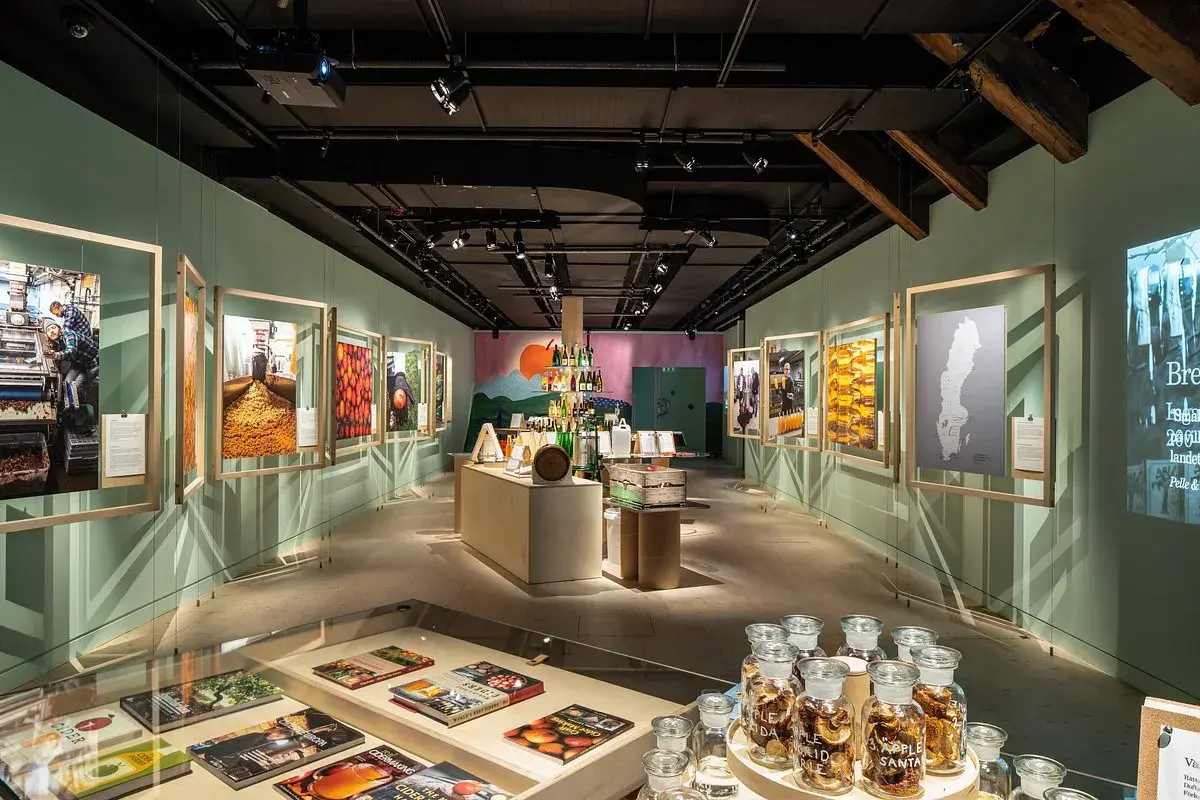 Utställning på Spritmuseum med bilder av produktion och ingredienser, samt flaskor med äppelmust.