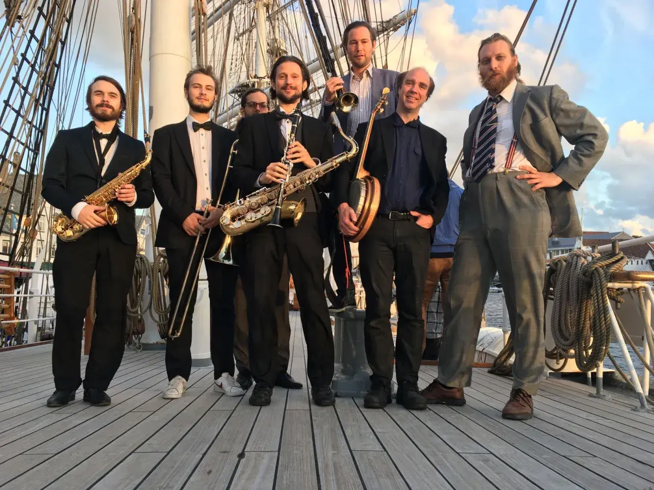 Ett storbandsjazz-band i Stockholm, med musiker som spelar saxofon, trumpet och banjo, poserar på ett fartyg.