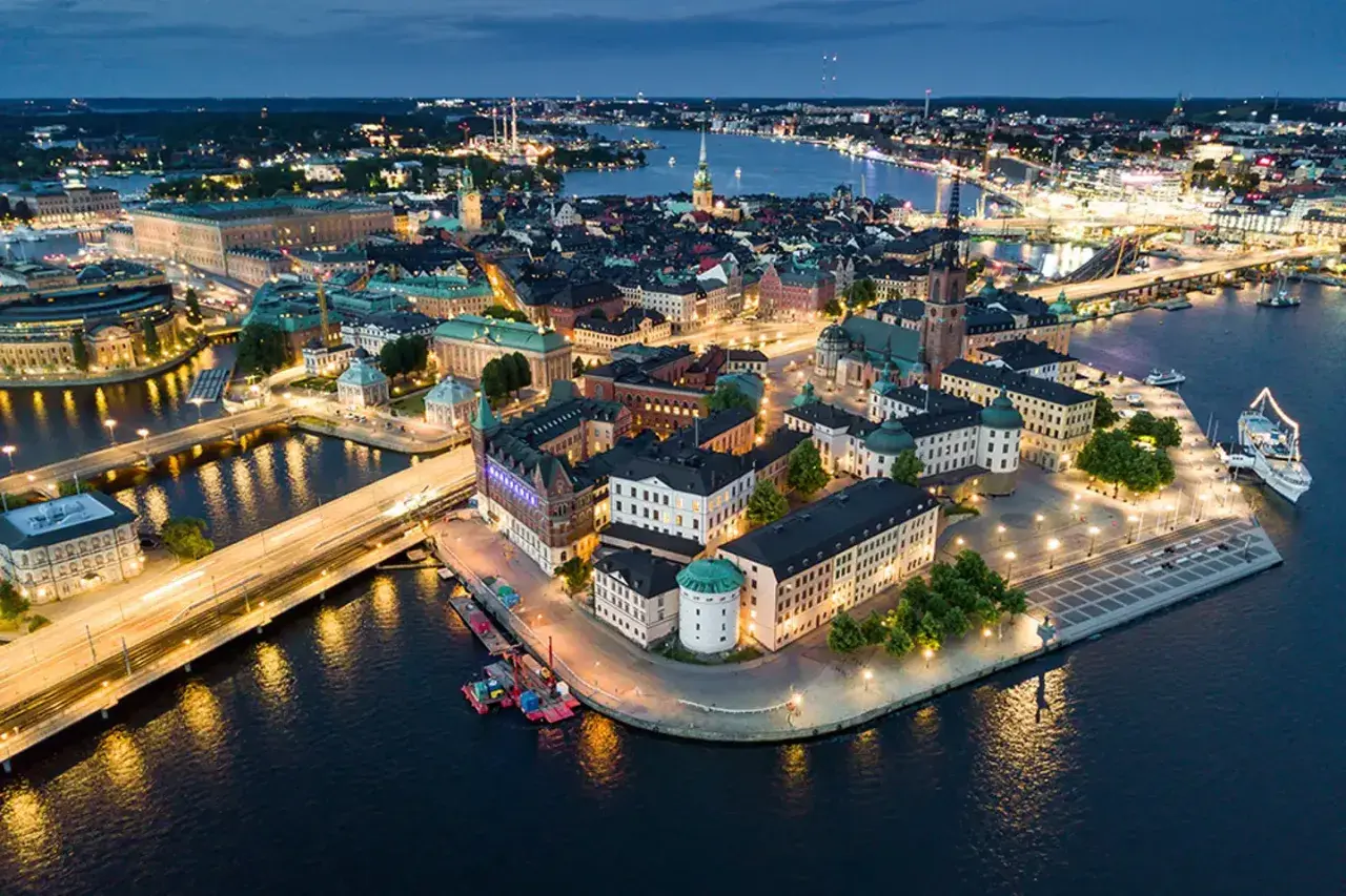 Vacker kvällsvy över Gamla Stan i Stockholm, Sverige. Upplysta byggnader och vatten reflekterar stadens ljus.
