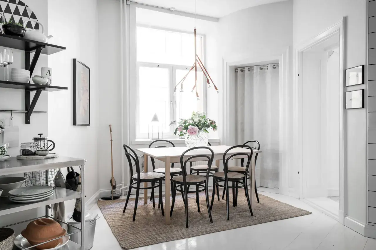 Ljust och luftigt kök med matbord och stolar, perfekt för matbord inredning inspiration. En stor vas med blommor pryder bordet.
