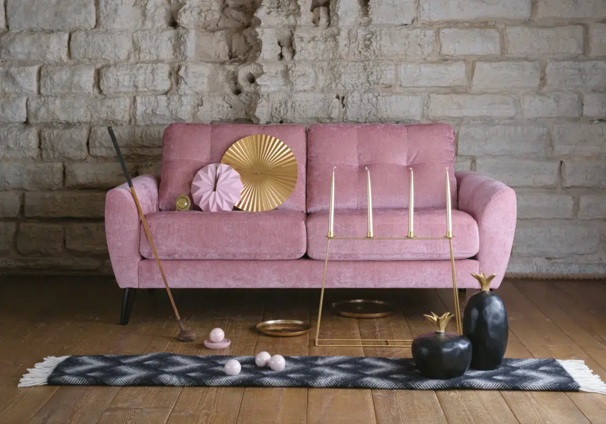 Rosa sammetssoffa med dekorativa föremål som ger soffa vardagsrum inspiration. En golfklubba, ljusstakar och ananasskulpturer skapar en unik atmosfär.