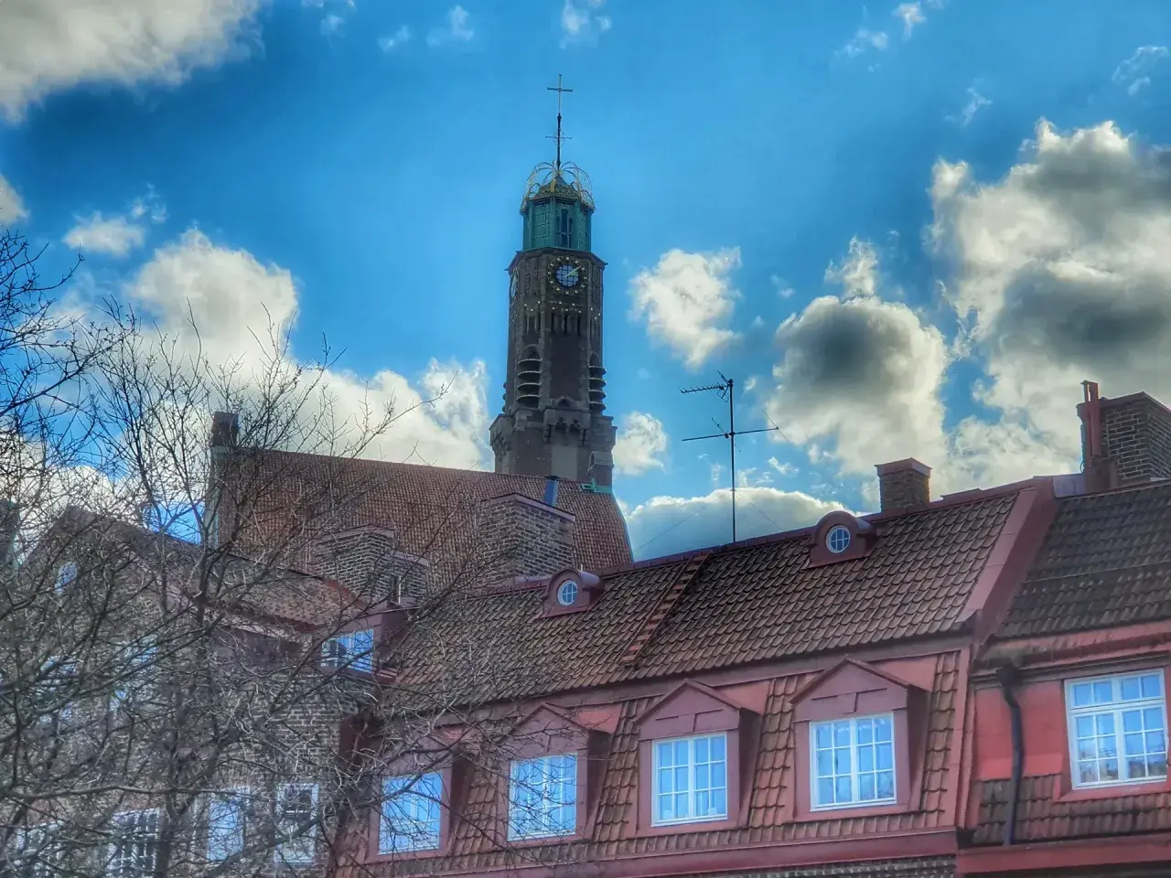 Engelbrekts kyrka reser sig mot en dramatisk himmel med moln. Kyrktornet har en klocka och en grön kupol.