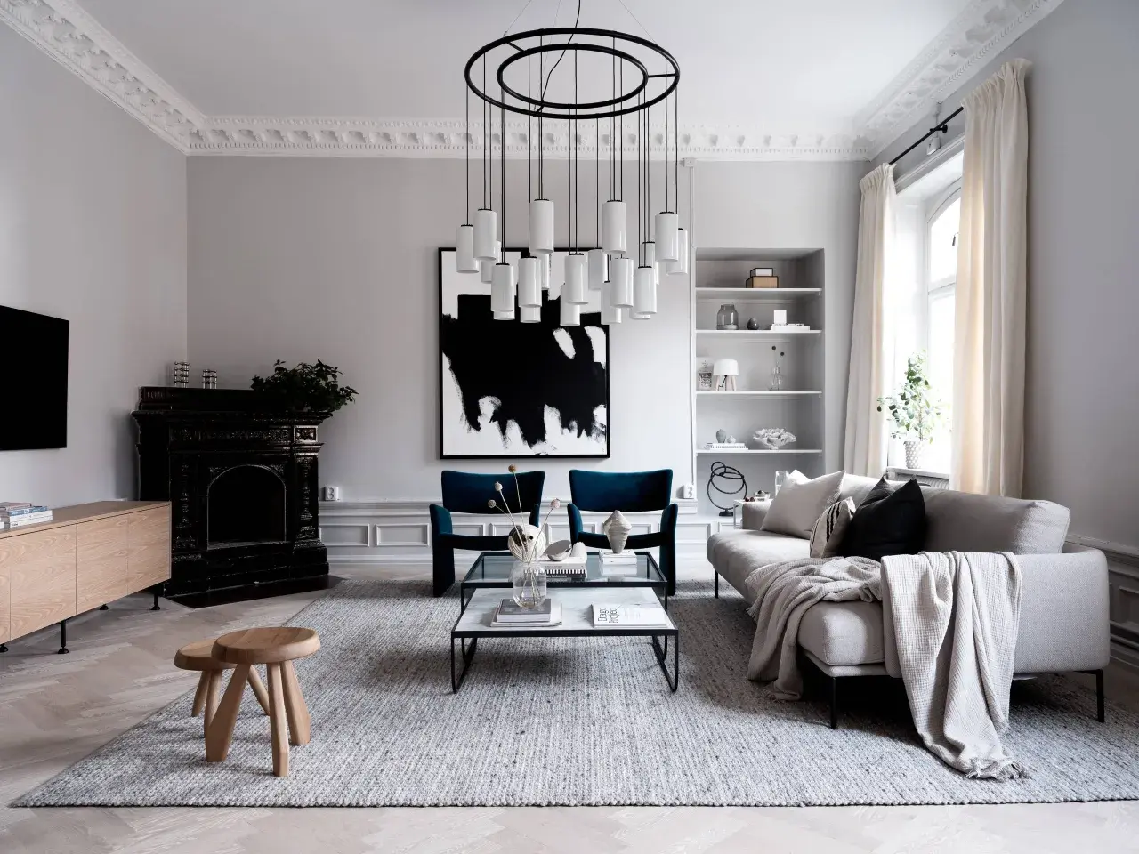 En modern skandinavisk inredning med en abstrakt skulptur som konstverk. En elegant taklampa och en svart öppen spis bidrar till rummets karaktär.
