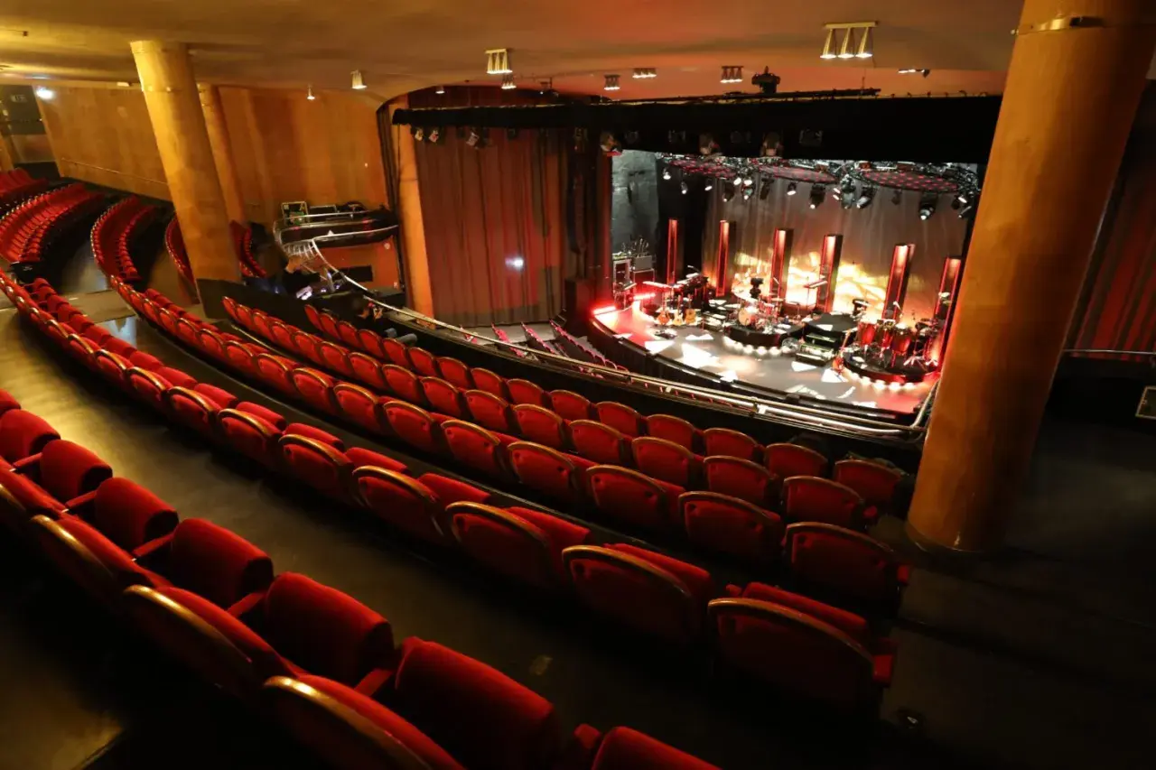 Tomma röda sammetsstolar i en teater, redo för publiken. Scenen är upplyst med instrument och redo för en konsert. En av många fina konsertlokaler i Stockholm.