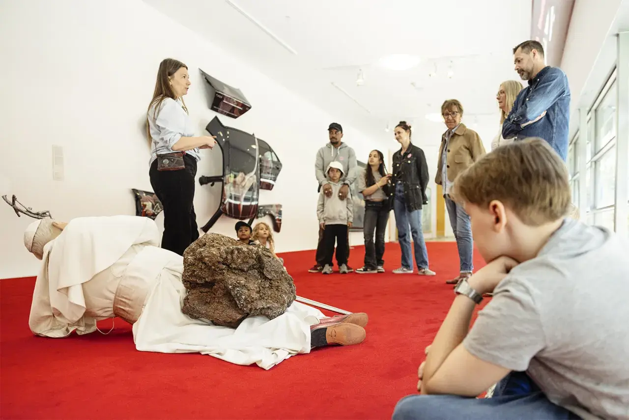 En grupp besökare, inklusive barn, lyssnar på en guide vid en konstinstallation på Moderna Museet Stockholm.