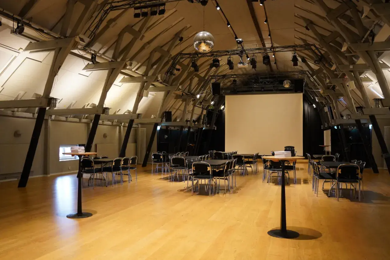 Stora, ljusa lokaler med trägolv och synliga takbjälkar, redo för ett event i workshop Stockholm.