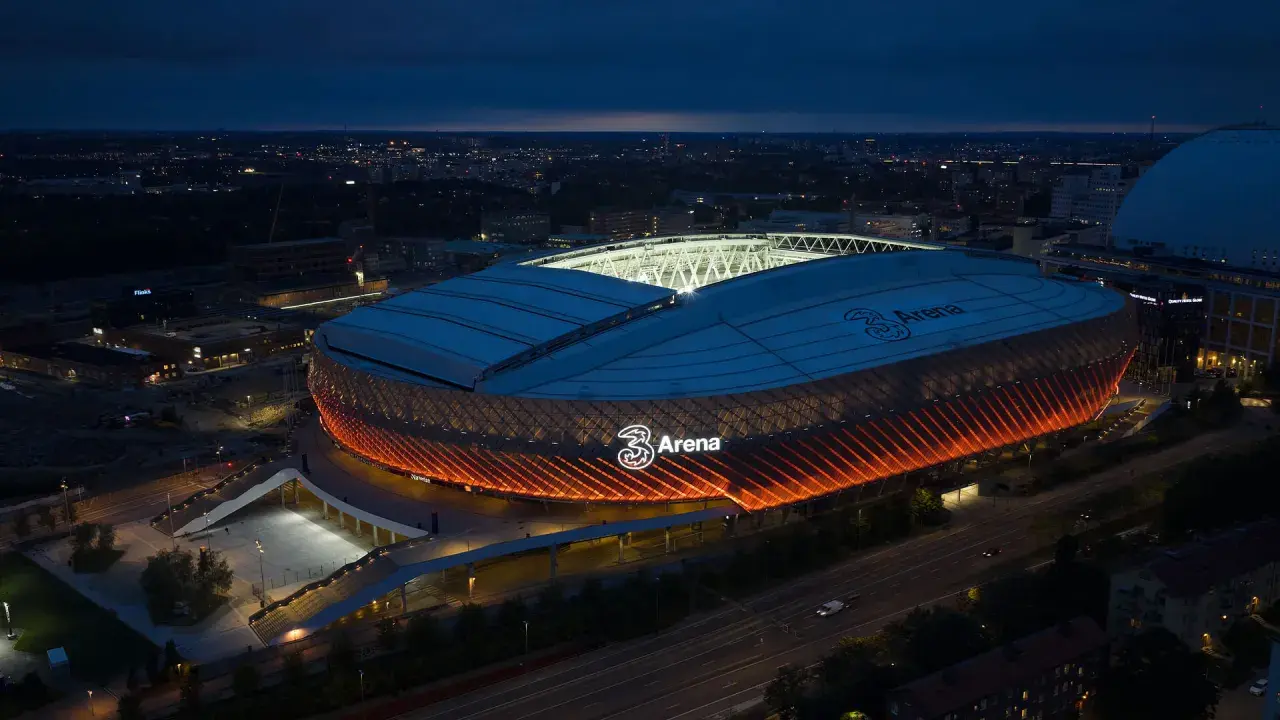 Tele2 Arena i Stockholm lyser upp natthimlen med sitt orangea sken. En ikonisk plats för evenemang.