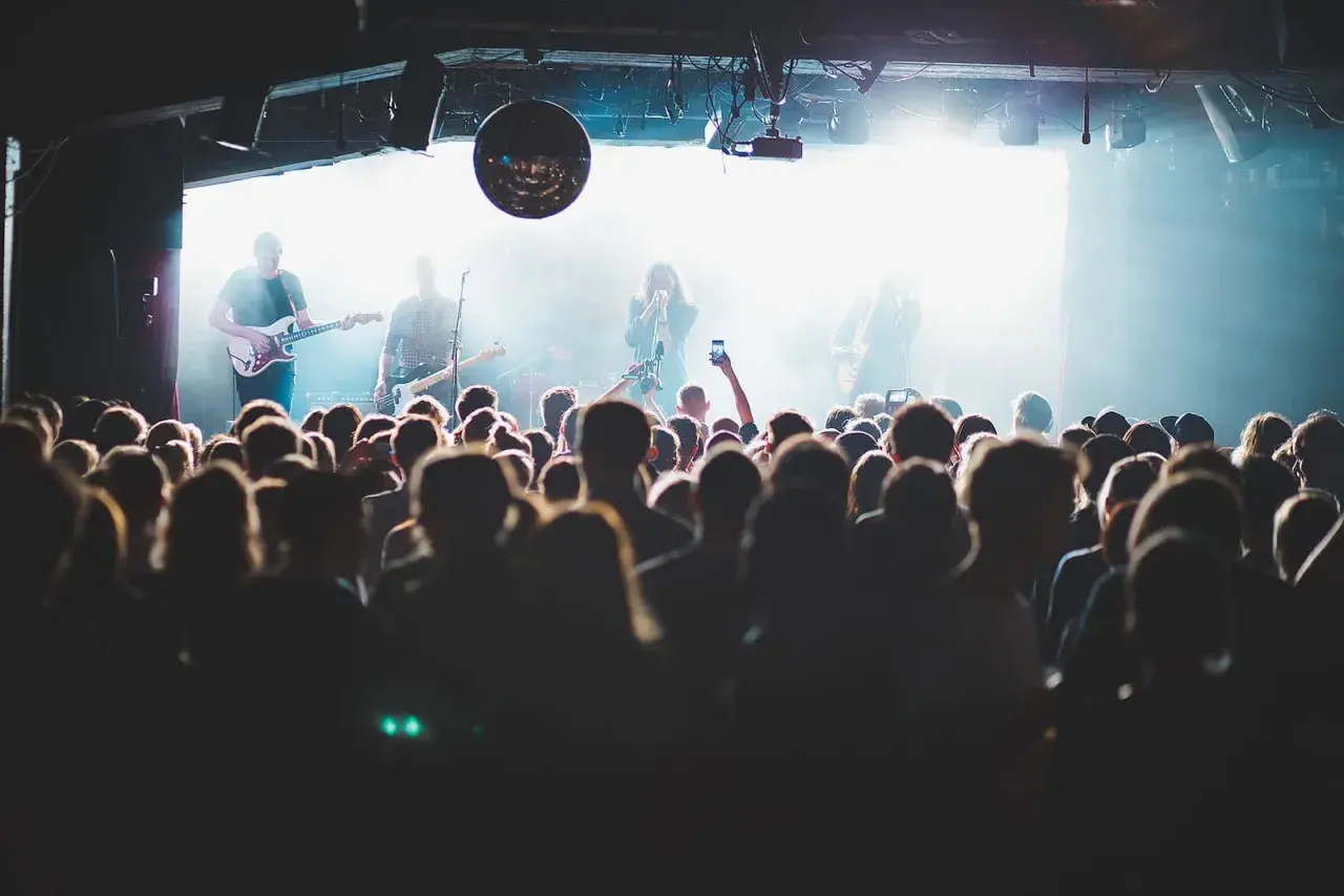 Publik njuter av en konsert i Stockholm idag. Bandet spelar på scenen medan publiken filmar med sina mobiler.