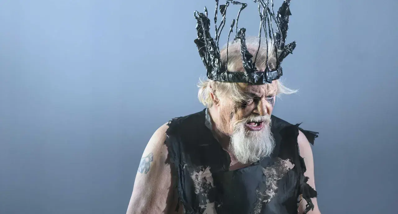 En skådespelare som Kung Lear på Dramaten, med en taggig, svart krona och trasiga kläder.
