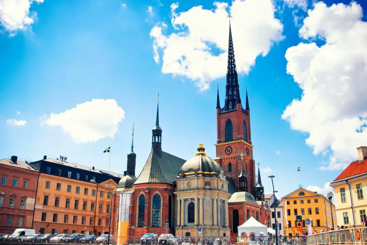 Stadshuset i Gamla Stan, Stockholm, med sina torn och en gul byggnad under en blå himmel med moln.