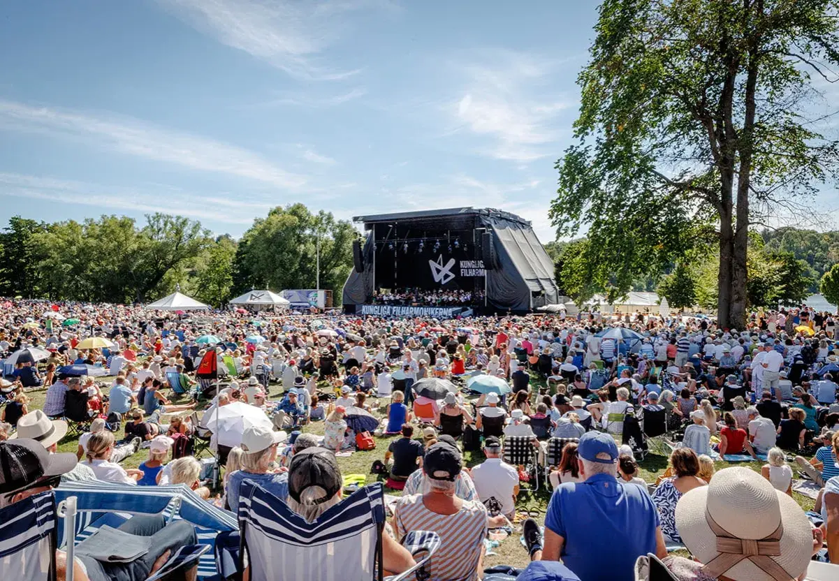 Stor publik njuter av en utomhuskonsert med Kungliga Filharmonikerna. Soligt och glatt!