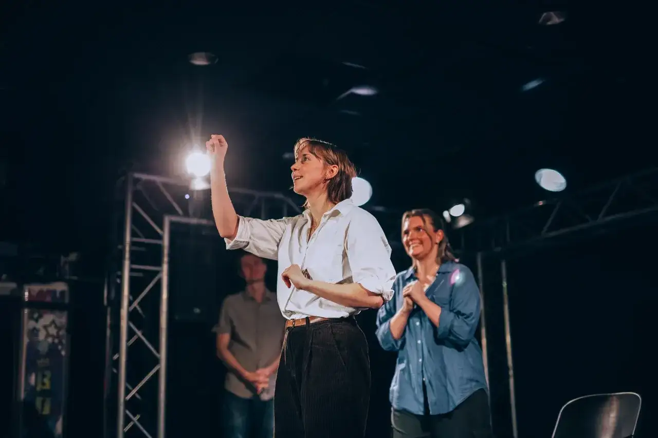 Scen fr&aring;n en improv-f&ouml;rest&auml;llning i Stockholm. En kvinna med vit skjorta gestikulerar, medan en annan kvinna ler bakom henne.