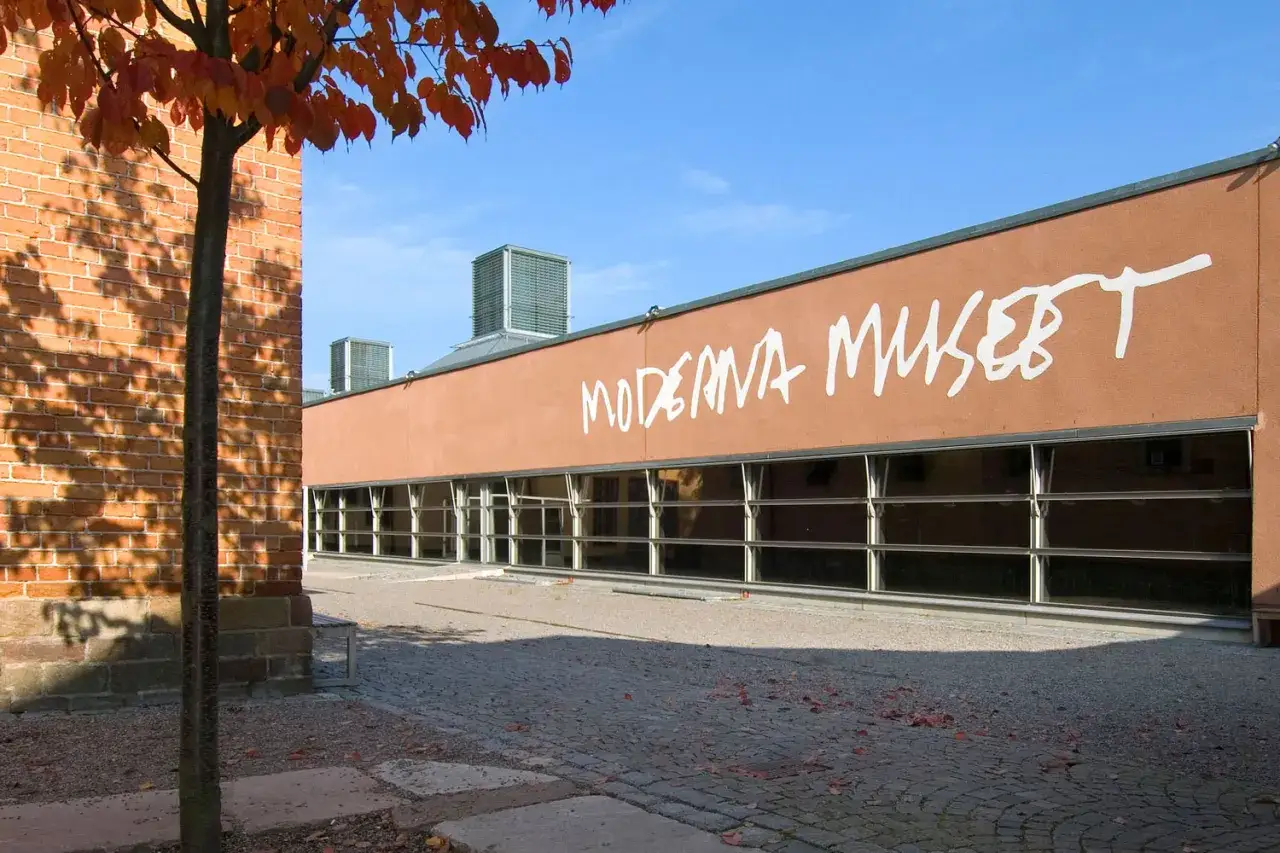 Moderna Museet Stockholm med orange fasad och stora fönster. Höstfärger på trädet.