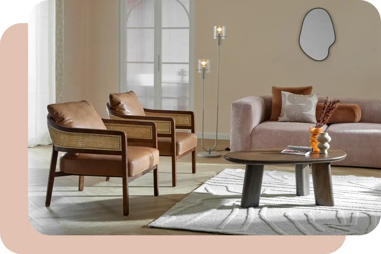 Mysig lounge med 60-tals inredning: läderfåtöljer, rosa soffa, träbord och en abstrakt spegel.