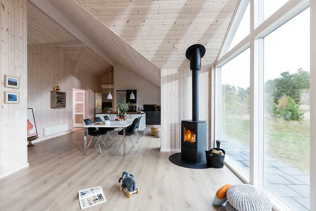 Varmt och mysigt vardagsrum med öppen spis, matplats och stora fönster. Perfekt för hygge danska-stunder.