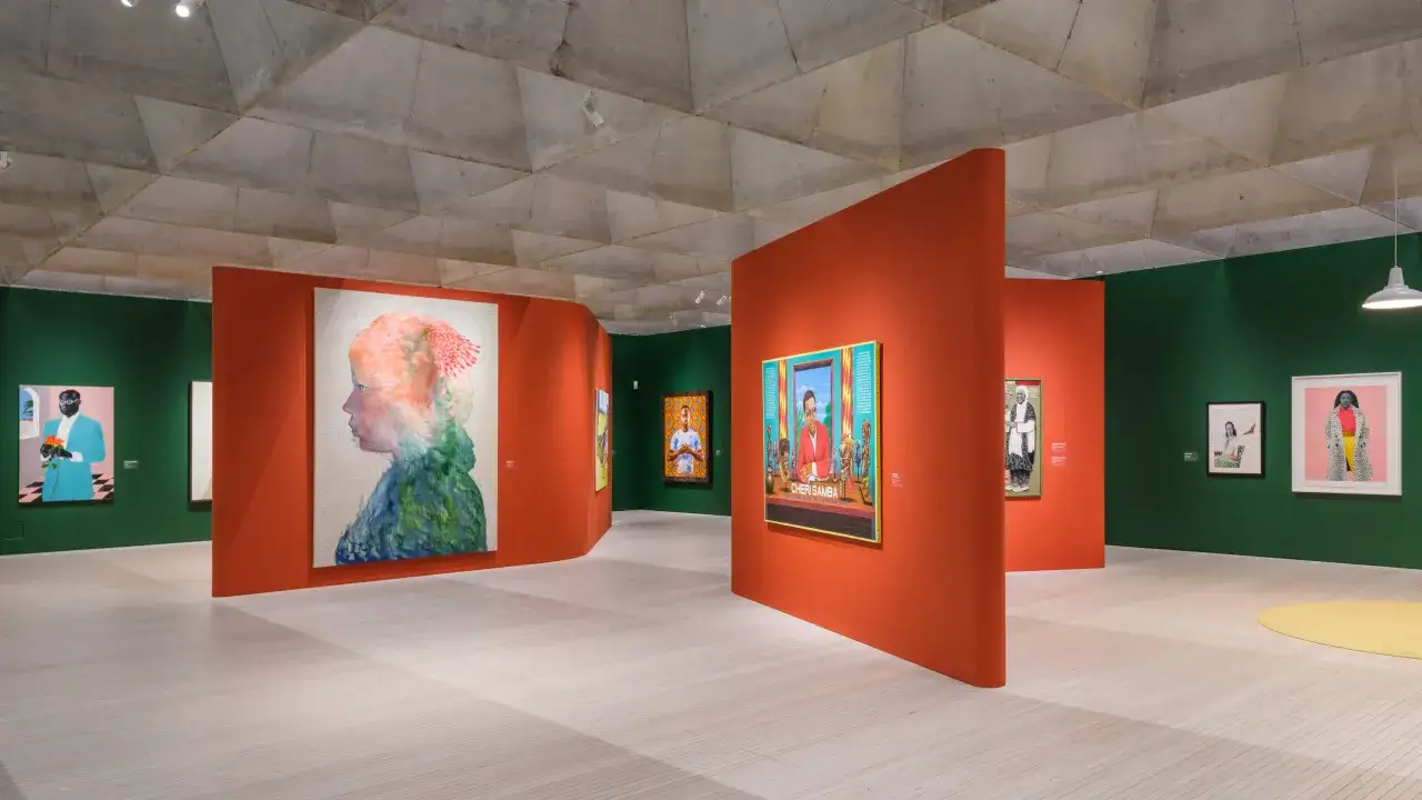 Konstutställning med färgstarka porträtt i ett modernt museum centrala Stockholm. Orange väggar och gröna ytor skapar en dynamisk miljö.