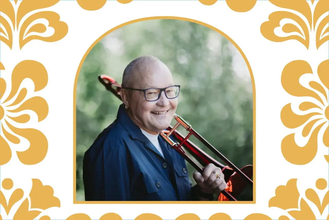 En glad man med glasögon håller i en trombon, redo för jazz på Skansen.