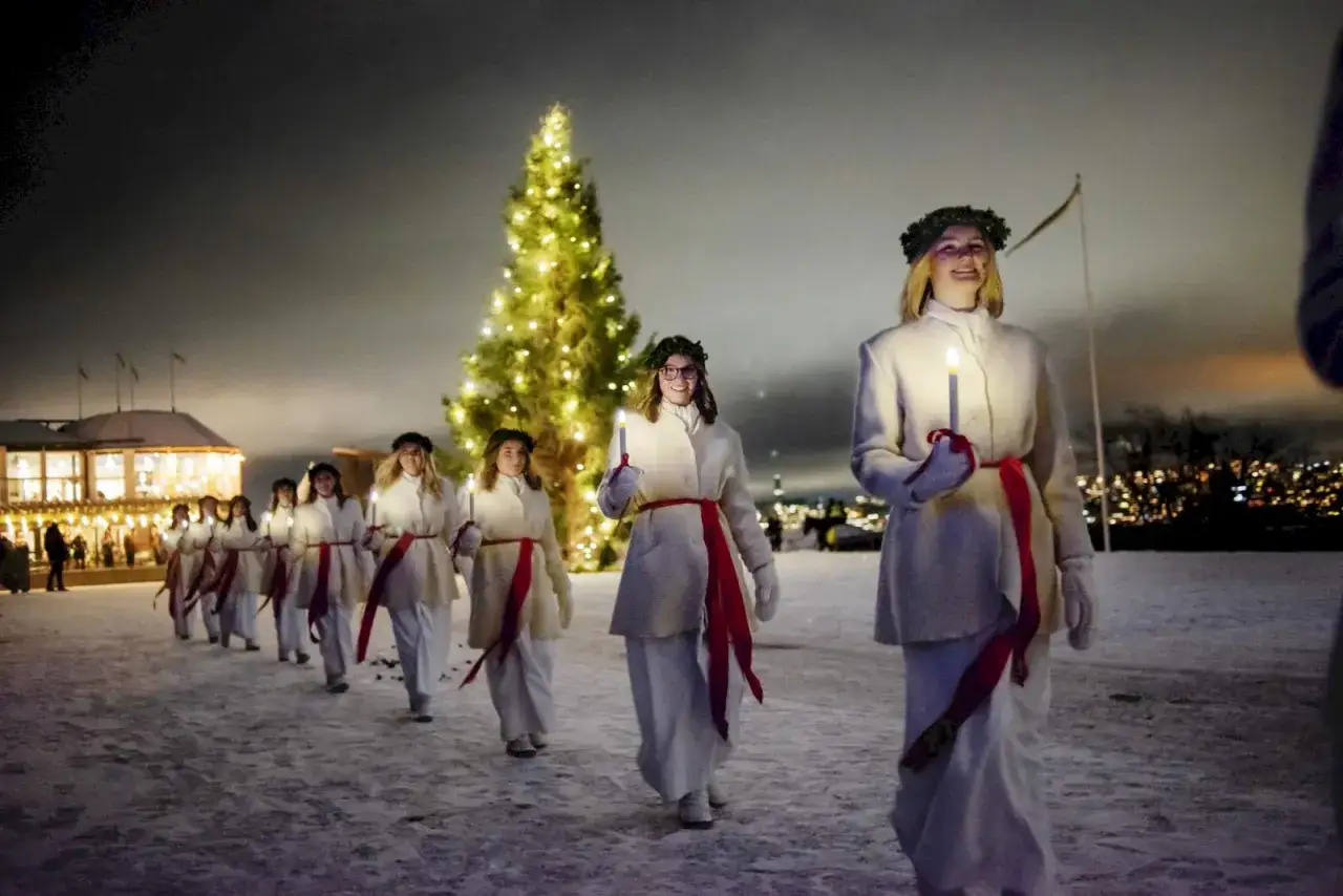 Lucia-tåg i snöig julnatt i Stockholm, med en glittrande julgran och ljus.