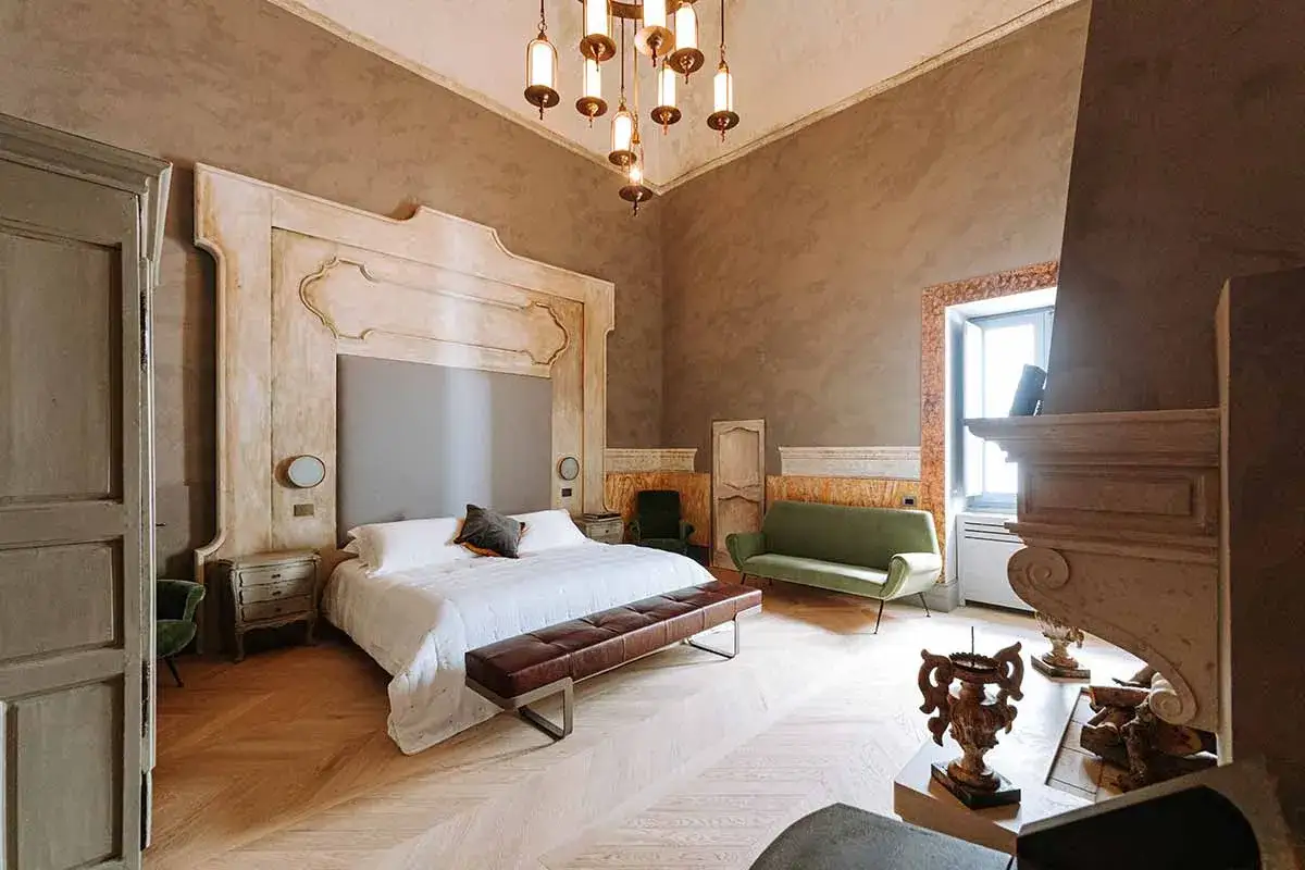 Ett lyxigt hotellrum med en stor säng, grön soffa och en imponerande öppen spis. Den eleganta hotellrum inredning skapar en inbjudande atmosfär.