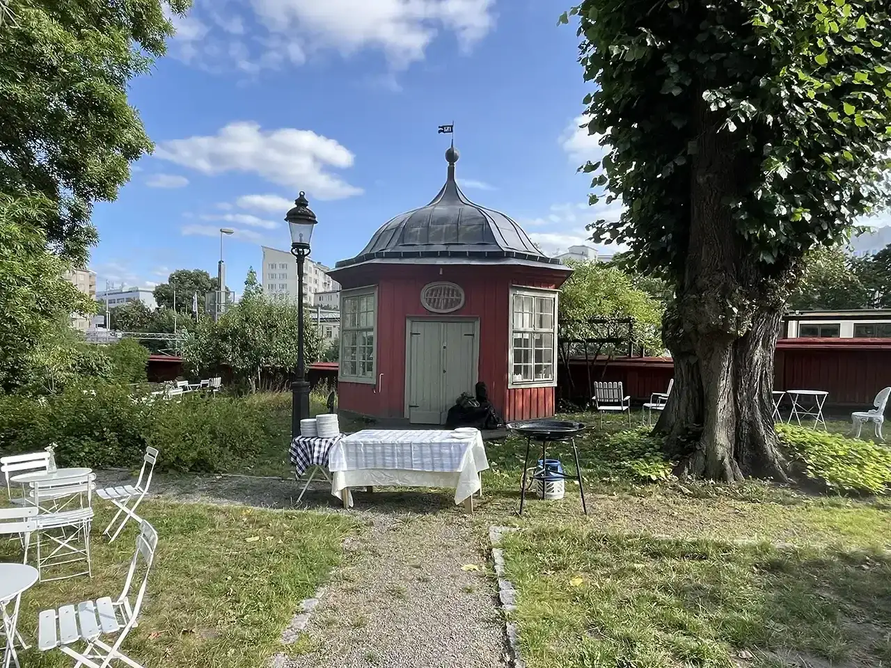 En röd paviljong vid Ekermanska malmgården, med bord dukade för fika och grill.