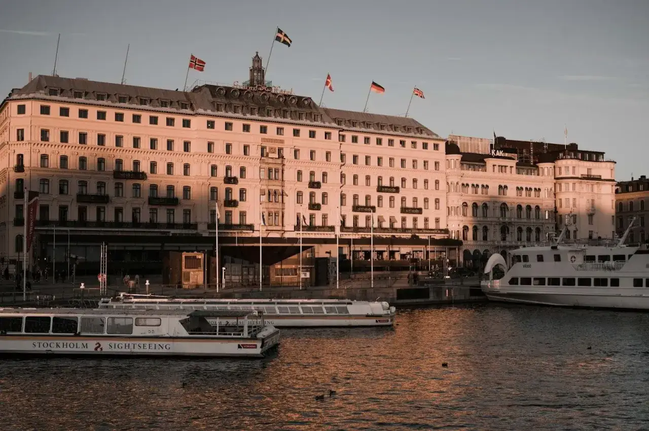 Vackert kv&auml;llsljus &ouml;ver Grand H&ocirc;tel i Stockholm. Perfekt f&ouml;r en romantisk date night Stockholm med utsikt &ouml;ver vattnet och b&aring;tarna.