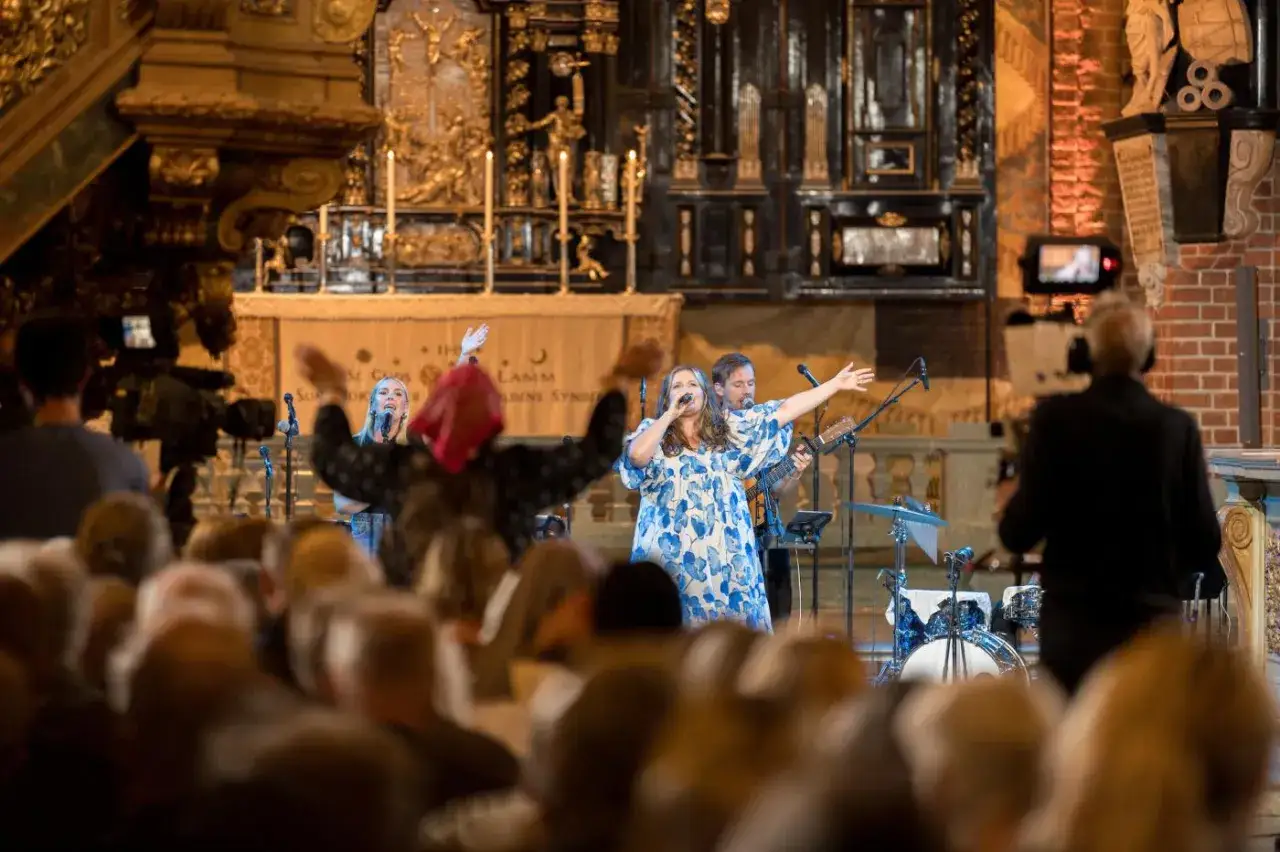 Storkyrkan bjuder på en gripande musikupplevelse med sångerskor och musiker framför en imponerande altartavla.
