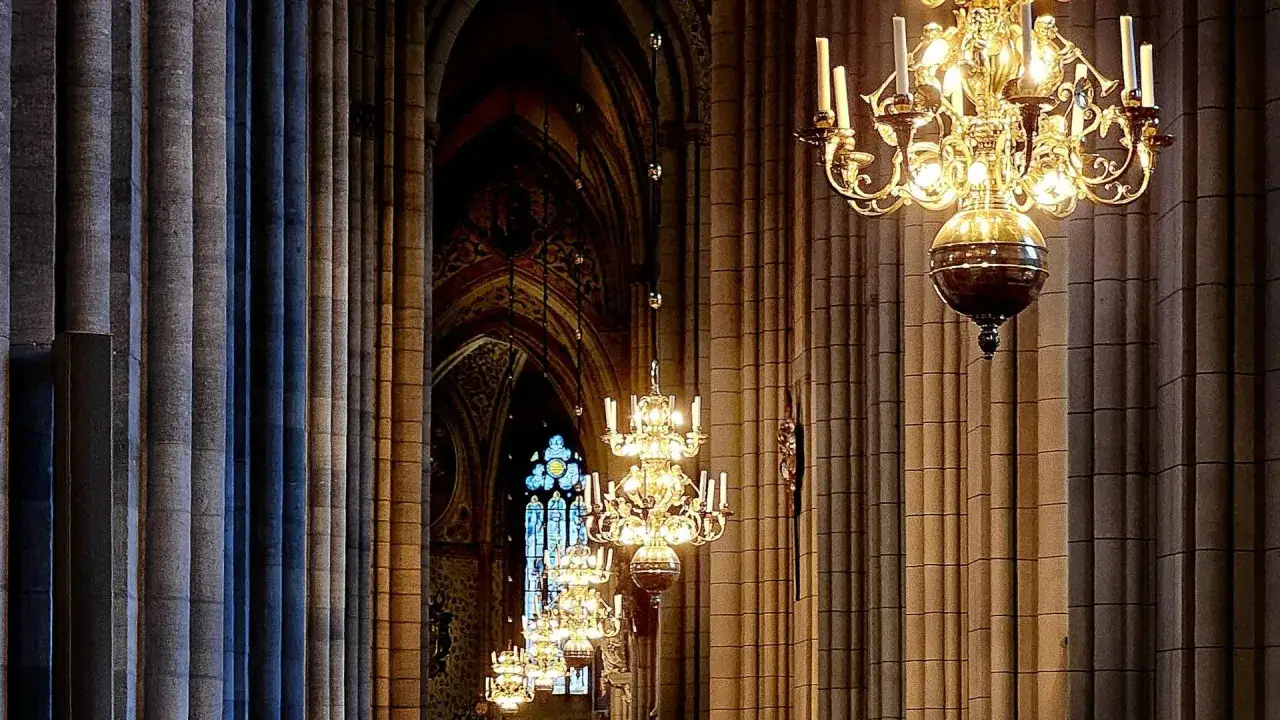Gyllene ljuskronor h&auml;nger i rad l&auml;ngs pelarna i Uppsala domkyrka. Ett vackert program f&ouml;r en speciell kv&auml;ll.