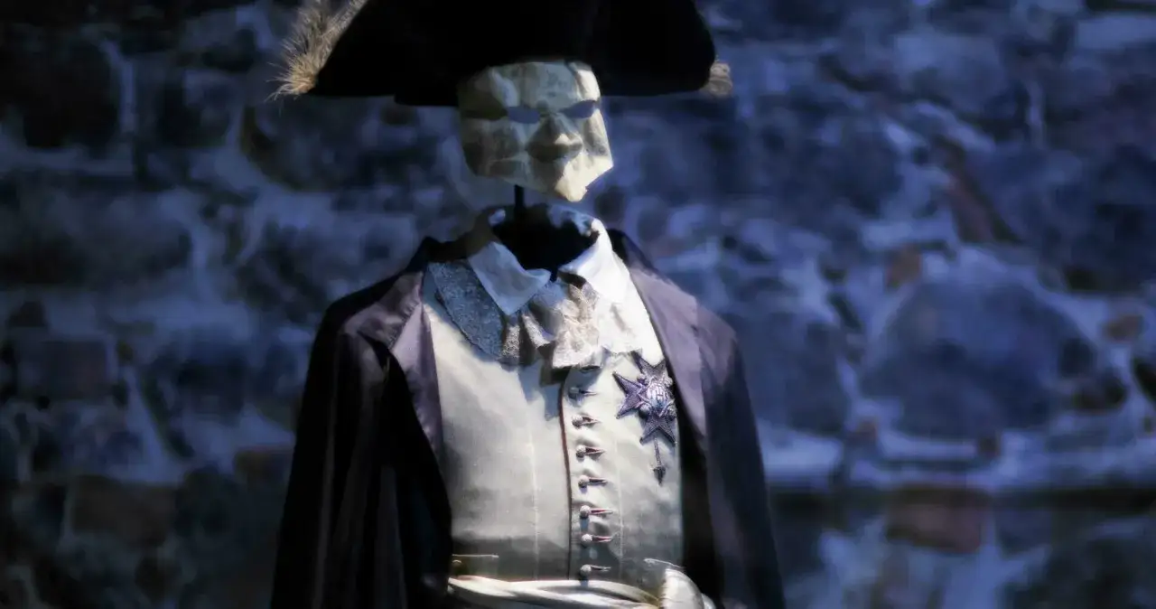 En maskerad figur i teaterkungen-stil med hatt och historisk dräkt.
