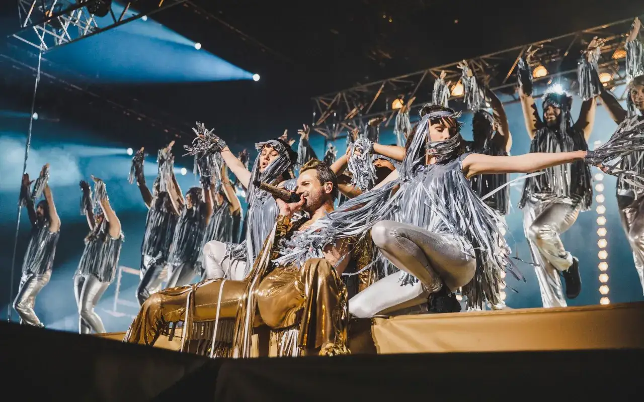 Jesus Christ Superstar i Stockholm: en gyllene artist sjunger medan dansare i silverglänsande dräkter lyfter sina armar.