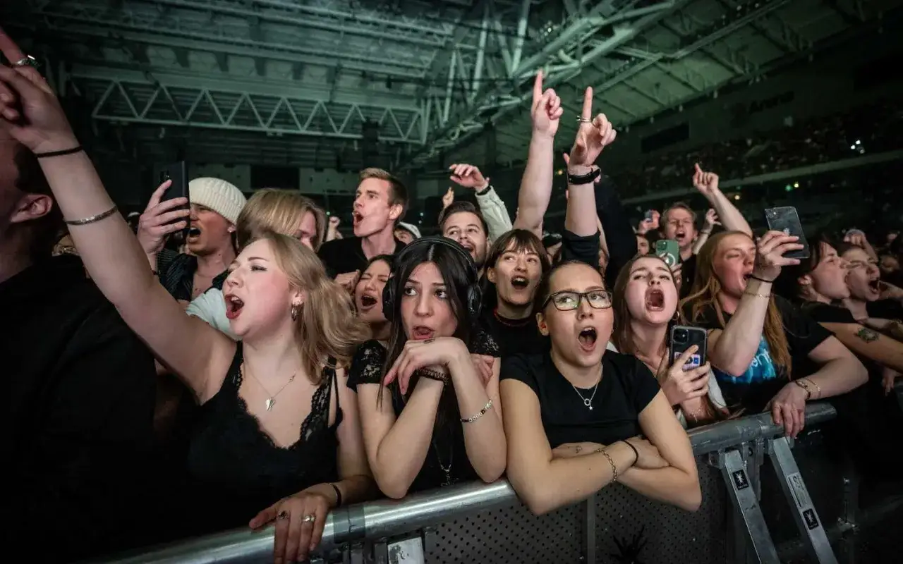 Publiken jublar och sjunger med under en Tele2 Arena konsert. Många har händerna i luften och telefoner för att filma.