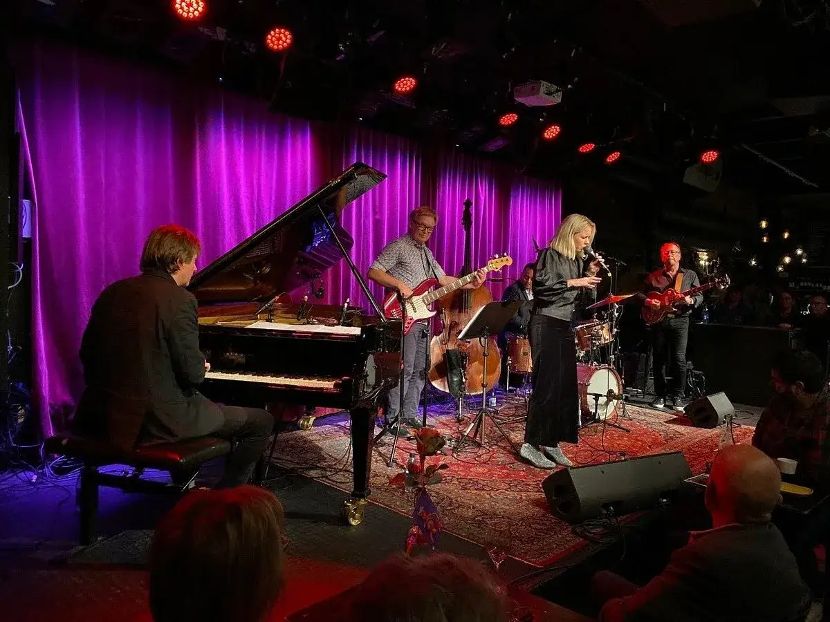 En jazzkväll i Stockholm med bandet på scen. Pianist, sångerska, basist, trummis och gitarrist spelar under lila draperier.