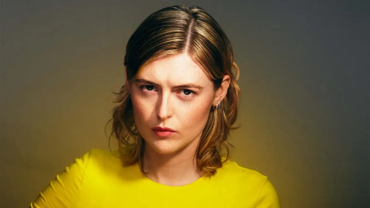 Ellen Krauss, med sitt blonda h&aring;r och gula tr&ouml;ja, ser intensivt in i kameran. En bild som f&aring;ngar energin inf&ouml;r en kommande ellen krauss konsert.