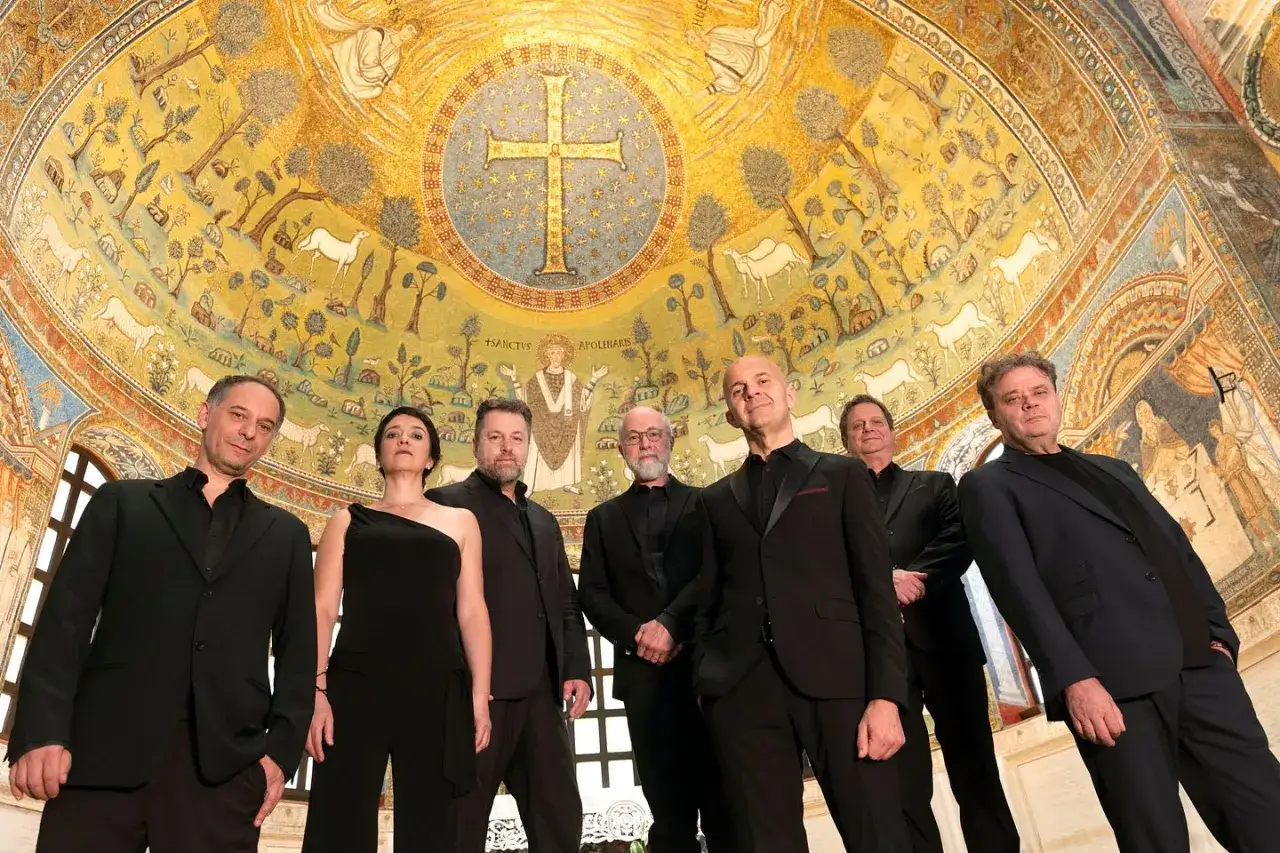 Ensemble i svart framför en gyllene mosaik med kors och djur. Kanske en del av ett tidigt musikfestival.