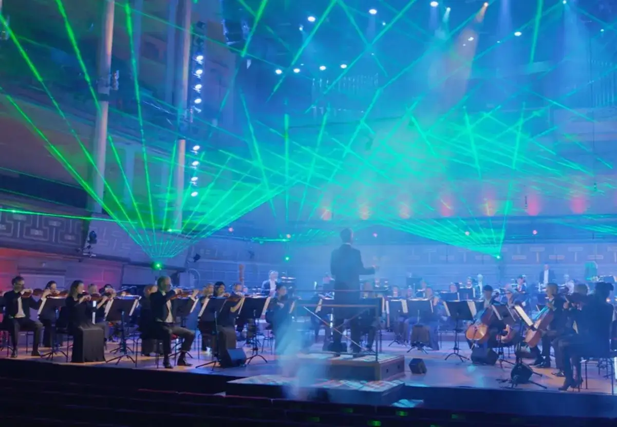 En orkester spelar under en imponerande ljusshow med gr&ouml;na laserstr&aring;lar. En minnesv&auml;rd konsert avicii arena.