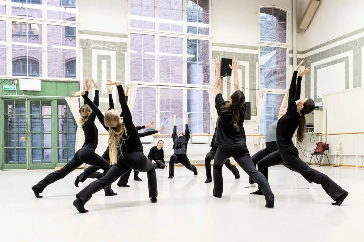Dansare i svarta kläder övar en koreografi i en ljus studio. Moderna dansteatern är en plats för kreativitet och rörelse.