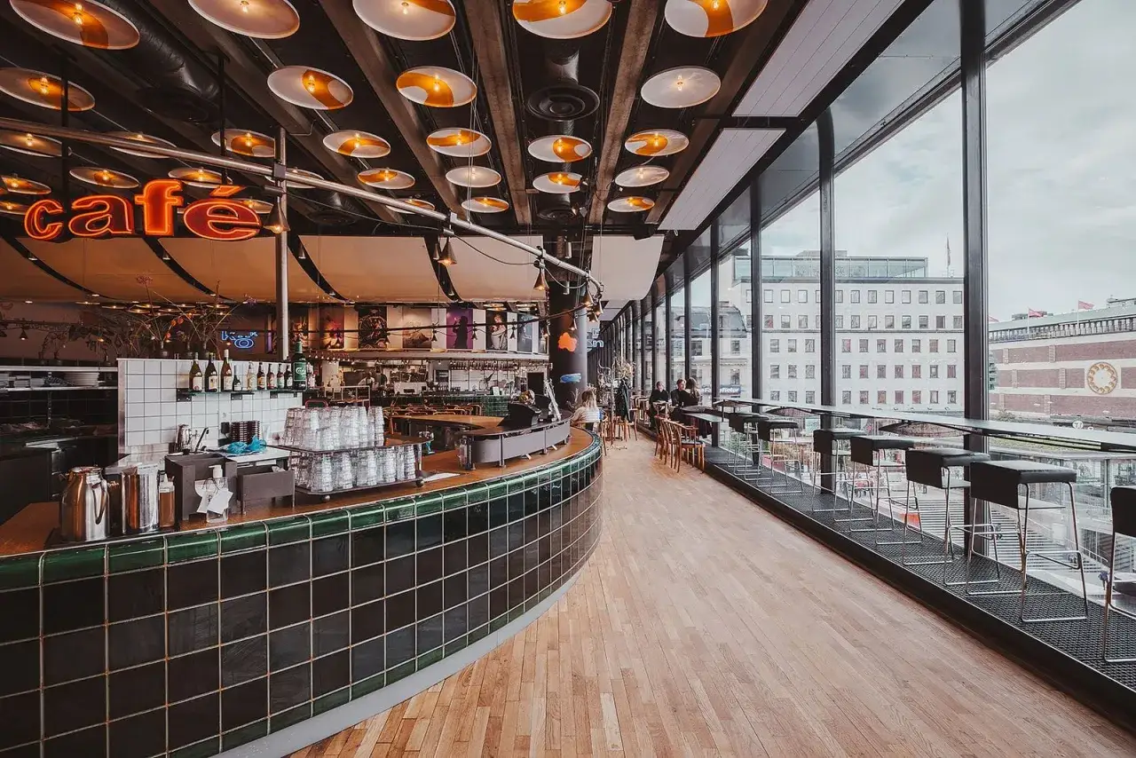Mysig caf&eacute;inredning med en l&aring;ng bardisk och f&ouml;nster med utsikt &ouml;ver stadens puls. En perfekt plats att koppla av p&aring; vid kulturhuset Sergels Torg.